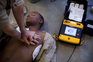 A person performing CPR on an unresponsive individual with an AED (LIFEPAK 1000) analyzing heart rhythm.